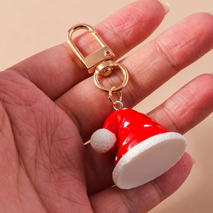 Detalle de un llavero de gorro navideño en resina roja con un cierre de metal dorado