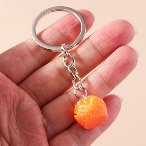 Realistic orange fruit keychain with textured surface held in hand for scale detail