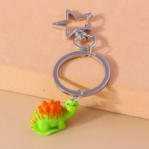 Detailed close-up of green dinosaur keychain with star-shaped silver carabiner clip