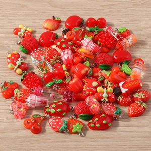 Detailed view of red resin fruit and heart charms with metal loops for DIY jewelry making
