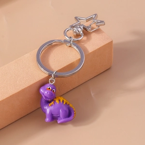 Close-up of cute purple cartoon dinosaur keychain with star-shaped silver metal clasp