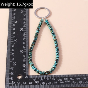 Dettaglio del portachiavi con perline turchesi, anello d'argento e scala di misura