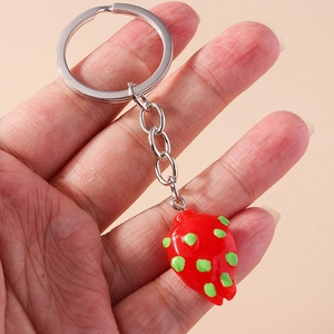 Detail of realistic red strawberry keychain held in hand with silver metal chain ring
