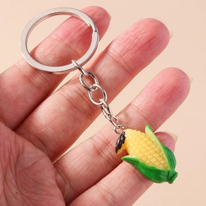 Detailed view of a realistic yellow corn keychain charm held by hand with silver ring