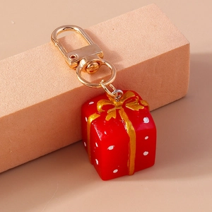 Detalle de llavero de caja de regalo roja de Navidad con lazo dorado y puntos blancos