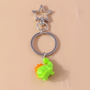 Close-up of green resin dinosaur keychain with orange spikes and star-shaped silver carabiner