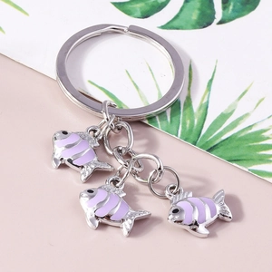 Détail de mignons pendentifs carpes koi en émail violet avec porte-clés doré et maillons