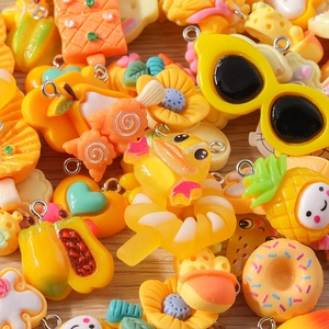 Detailed macro view of assorted resin charms featuring flowers and fruit for DIY jewelry