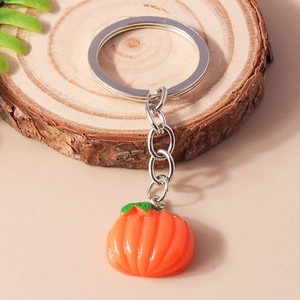Detailed close-up of a realistic orange pumpkin keychain charm on a rustic wood slice background