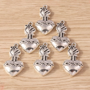 Vintage sacred heart alloy pendants with thorns and flame crown on wood background