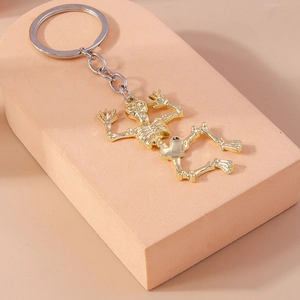 Close-up of a gold skeleton keychain accessory for backpacks on a pink pedestal