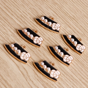 Pendentifs fleur dorée avec camélia blanc et perles sur fond en bois clair
