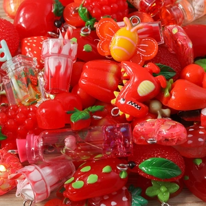 Flat lay of red resin charms including strawberries and dinosaurs for DIY jewelry making