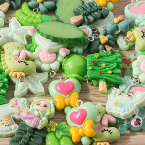 Close-up of green resin cartoon flower and fruit charms with metal hooks for DIY jewelry