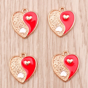 Detailed macro view of heart-shaped Yin Yang charms with red enamel and gold texture