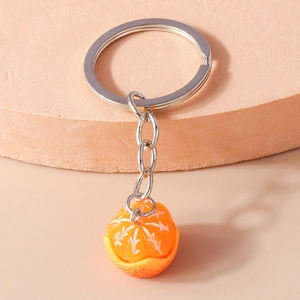 Detail of simulated orange resin keychain with realistic fruit texture on a round stand