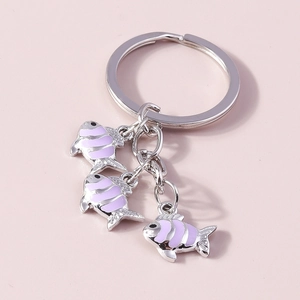 Détail de porte-clés poissons en émail argenté avec rayures mauves sur fond rose