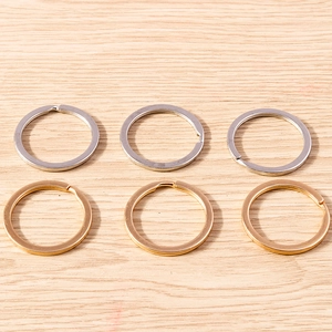 Flat round double-layer metal keyrings in gold and silver finish on wooden background