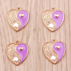 Detailed macro view of heart-shaped Yin Yang pendants in purple enamel and golden alloy finish