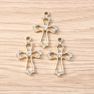 Detailed view of hollow rhinestone cross charms for DIY jewelry on wooden surface