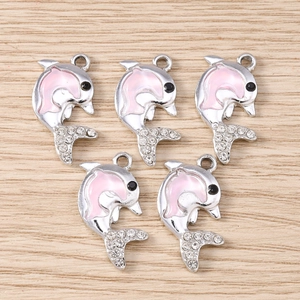 Dettaglio di ciondoli delfino in smalto rosa con base argentata e strass bianchi per DIY