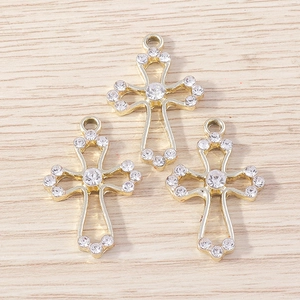 Detailed close-up of three gold cross pendants with sparkling rhinestones on wood