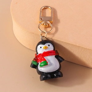 Detalle de un lindo llavero de pingüino con bufanda y cierre de metal dorado