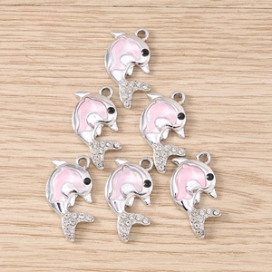 Dettaglio di ciondoli a forma di delfino in smalto rosa e argento per gioielli fai-da-te