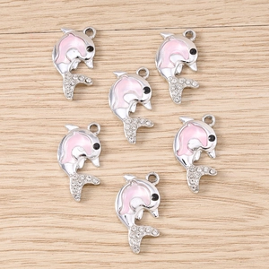 Dettaglio macro di sei ciondoli a delfino in smalto rosa con strass su base legno