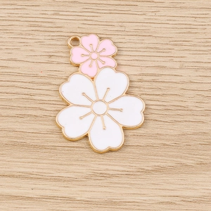 Detailed macro view of pink and white cherry blossom charms with gold metal edges for DIY