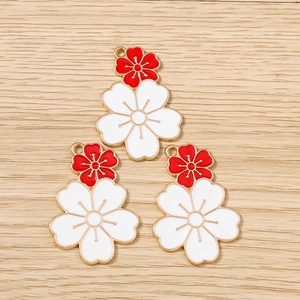 Macro shot of three double-layered cherry blossom flower charms with red and white enamel