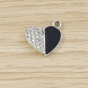 Macro detail of silver heart charm with sparkling rhinestones and black enamel finish