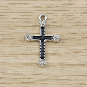 Detailed macro view of silver gothic cross pendant with black enamel and clear rhinestones