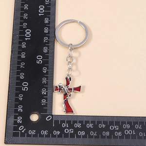 Gothic skull cross keychain with red enamel inlay shown with a scale ruler for size