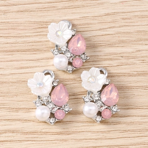 Makro-Detail von DIY-Blumenanhängern mit rosa Edelsteinen und weißen Kunstperlen