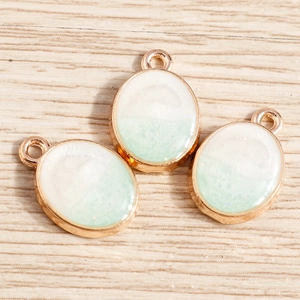 Détail de pendentifs ovales en résine dégradée blanc-vert avec base en alliage doré