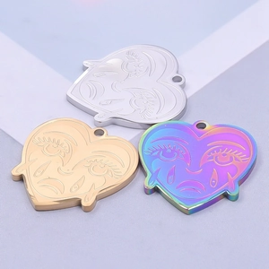 Three heart-shaped stainless steel pendants with engraved weeping face design in gold, silver, and rainbow