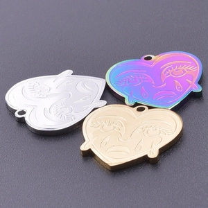 Macro detail of heart-shaped stainless steel charms with engraved sad face in three colors