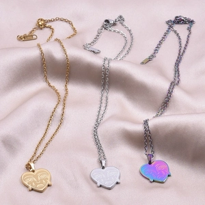 Detailed macro of heart pendants with teardrop face engraving in gold, silver and rainbow