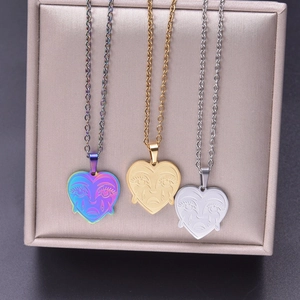 Detail of 18k plated stainless steel heart pendants with engraved crying face patterns