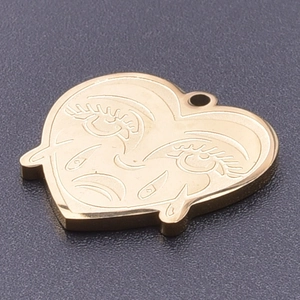 Detailed view of a golden heart-shaped stainless steel pendant with etched crying face design