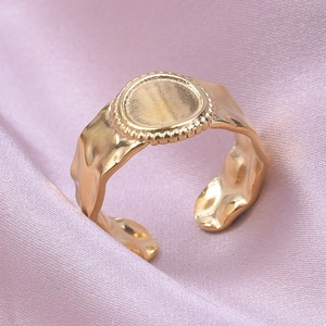 Macro shot of gold retro adjustable ring with hammered texture on purple satin fabric