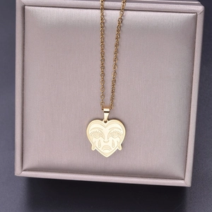 Macro shot of gold 18k plated heart pendant necklace with cartoon face in a gift box