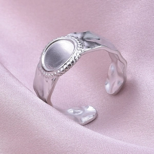 Macro shot of silver adjustable lava texture ring on pink satin fabric background