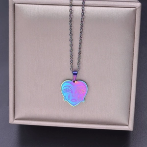 Macro view of rainbow stainless steel heart pendant featuring a crying face engraving