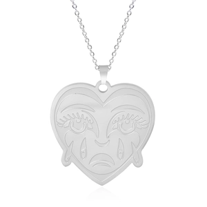 Macro shot of silver heart pendant with unique crying face engraving and fine chain