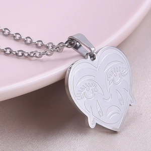 Macro detail of silver heart pendant with abstract face line art on thin chain