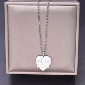 Detail of silver heart pendant with engraved sad face emoji on a delicate steel chain