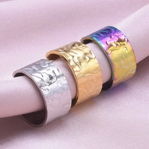 Macro detail of three wide textured stainless steel rings in silver, gold and rainbow finish