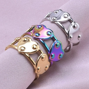 Detailed view of heart-shaped hollow rings in gold, silver, and rainbow on satin